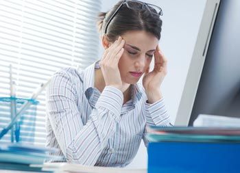 woman in office with migraine