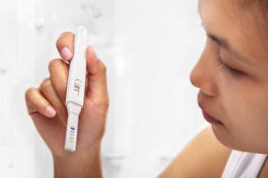 Asian woman looking at pregnancy test