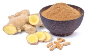 Photo of ginger root, ginger powder in bowl, and capsules of ginger powder